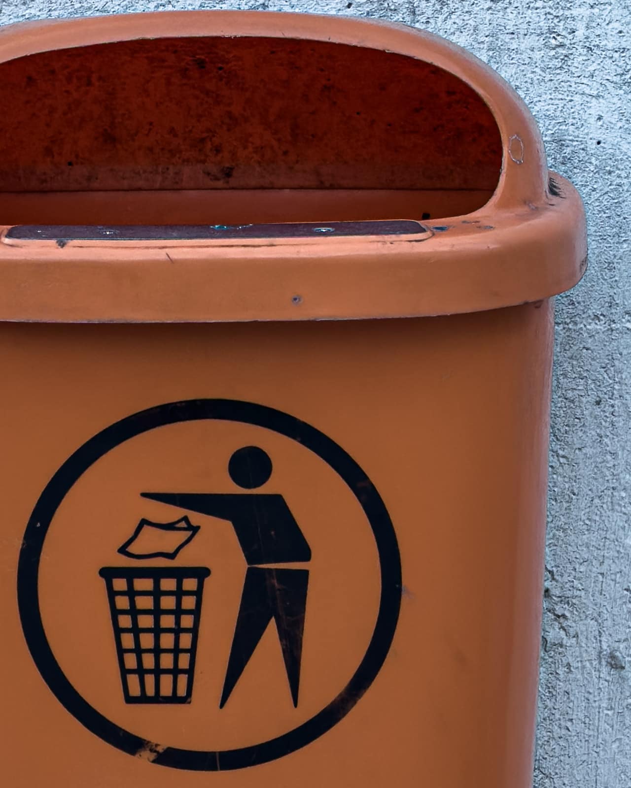 Trash bin symbol printed on an orange public bin in Zeltweg.