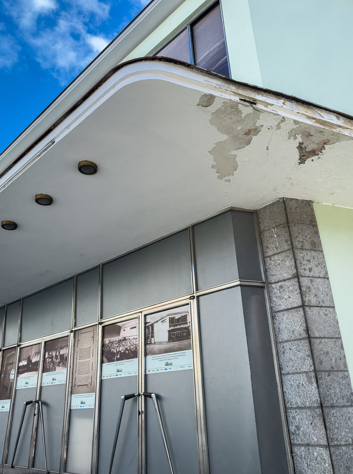 Former cinema building in Zeltweg, Austria, with worn facade and closed entrance.