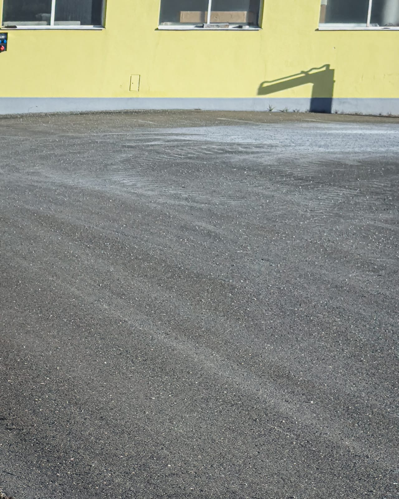 Empty paved surface beside an industrial building in Zeltweg.